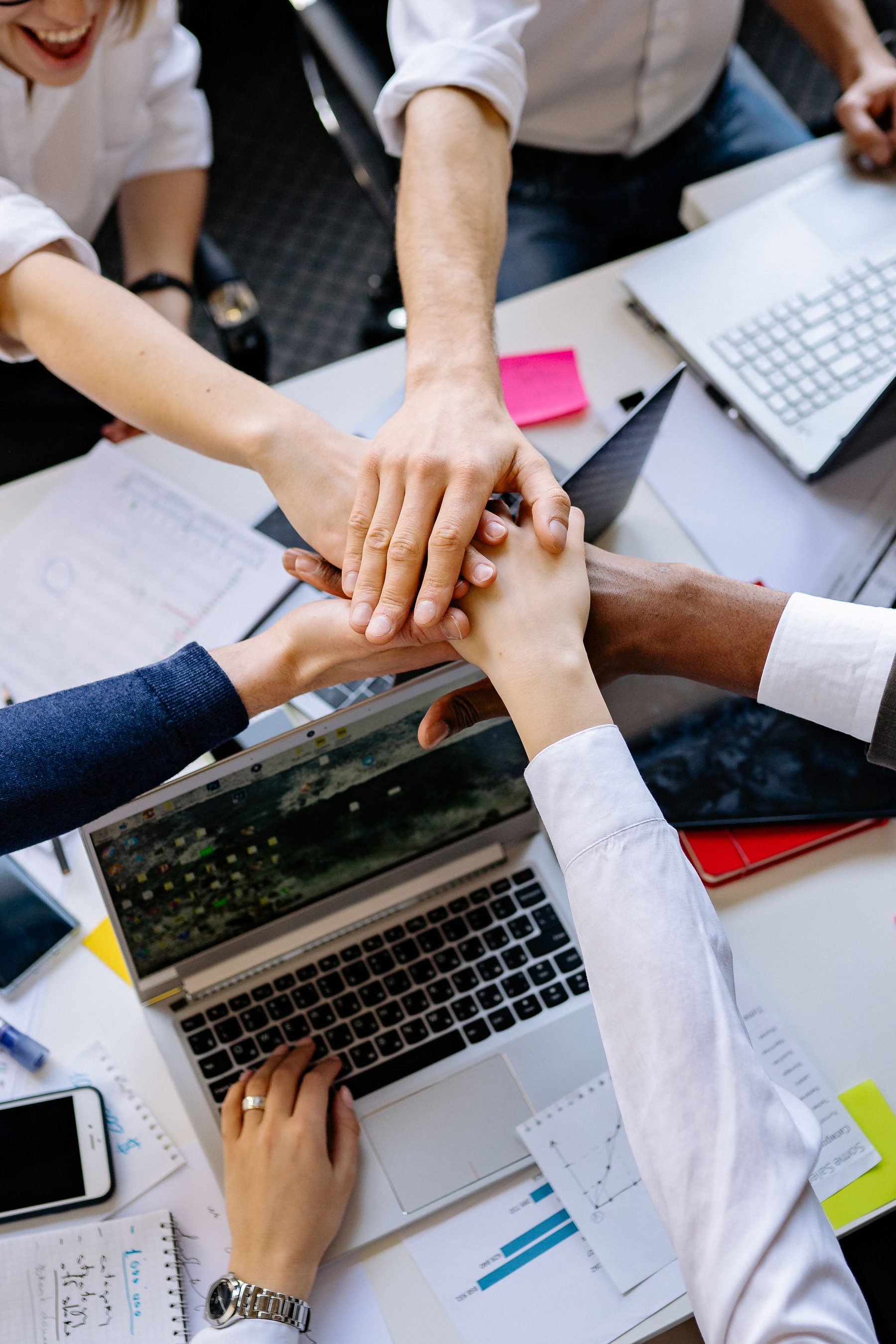Diverse team stacking hands together in unity
